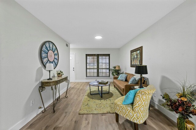 living room with light wood-type flooring, french doors, and a stone fireplace