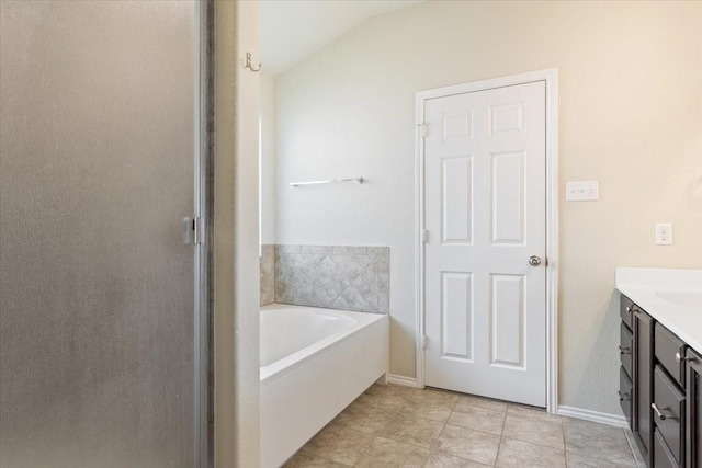 bathroom featuring vanity, vaulted ceiling, tile patterned floors, and a washtub