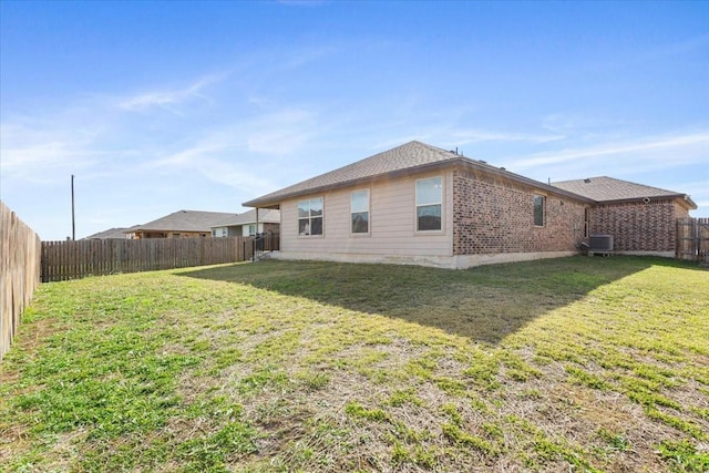 back of house with central AC unit and a yard