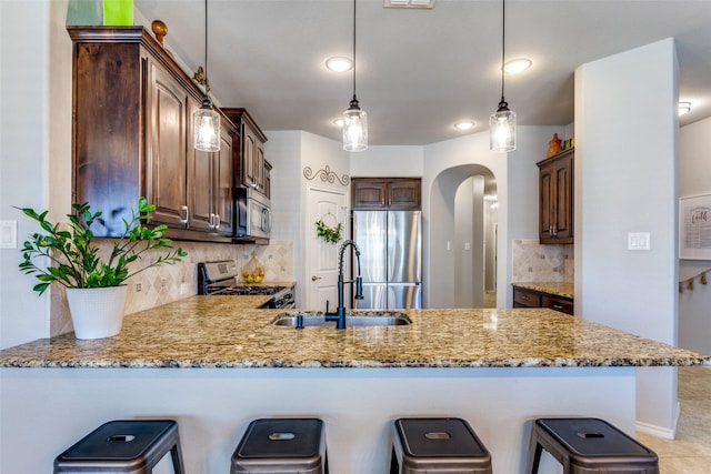 kitchen featuring decorative light fixtures, decorative backsplash, appliances with stainless steel finishes, and sink