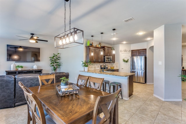 tiled dining area with ceiling fan and sink