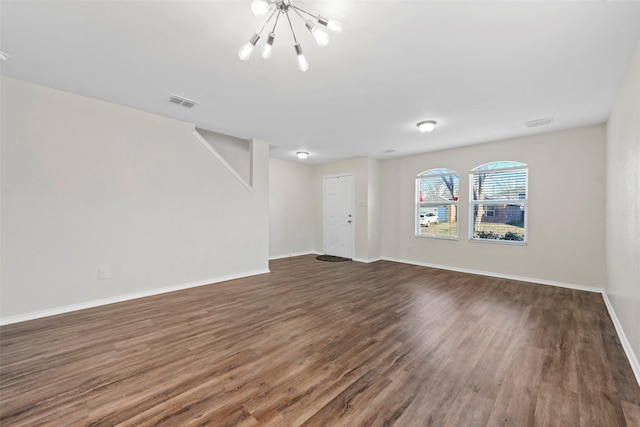 unfurnished living room with a chandelier and dark hardwood / wood-style floors