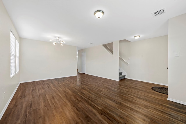 unfurnished living room featuring a chandelier and dark hardwood / wood-style flooring