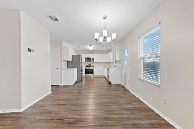 kitchen featuring pendant lighting, white cabinets, stainless steel appliances, and a chandelier