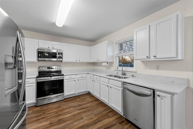 kitchen featuring white cabinetry, stainless steel appliances, dark hardwood / wood-style flooring, light stone countertops, and sink