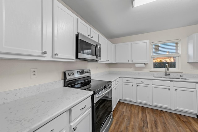 kitchen featuring white cabinetry, stainless steel appliances, dark wood-type flooring, light stone counters, and sink