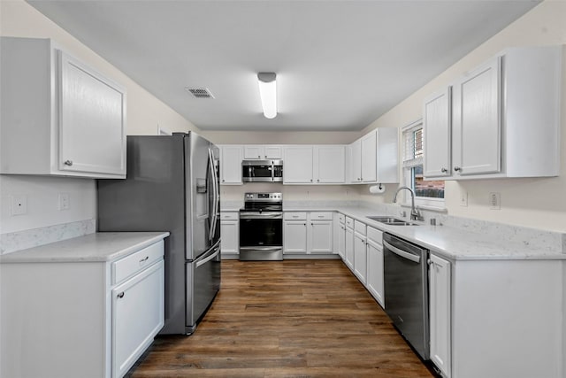 kitchen with appliances with stainless steel finishes, sink, dark hardwood / wood-style flooring, and white cabinetry