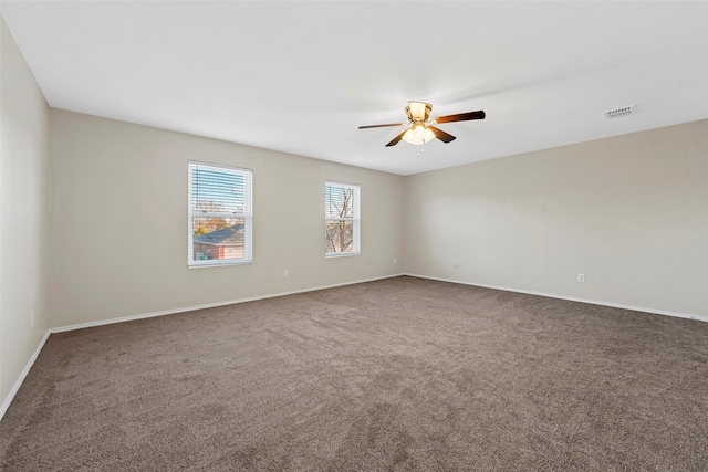 empty room featuring ceiling fan and dark carpet