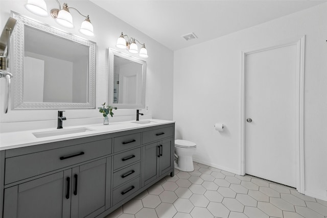 bathroom with toilet, vanity, and tile patterned floors