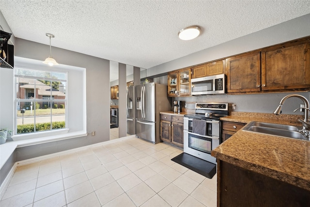 kitchen with a textured ceiling, stainless steel appliances, pendant lighting, and sink