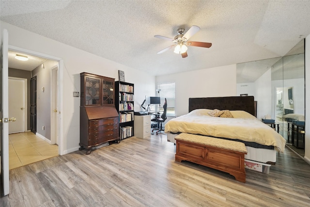 bedroom featuring ceiling fan, light wood-type flooring, and a textured ceiling