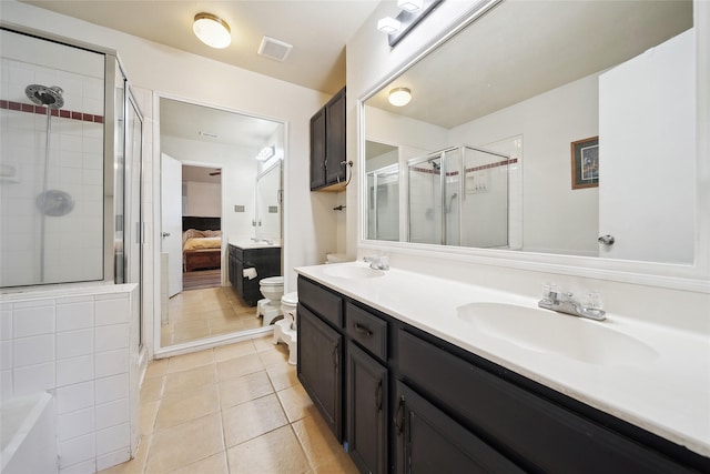 bathroom featuring a shower with door, toilet, vanity, and tile patterned flooring