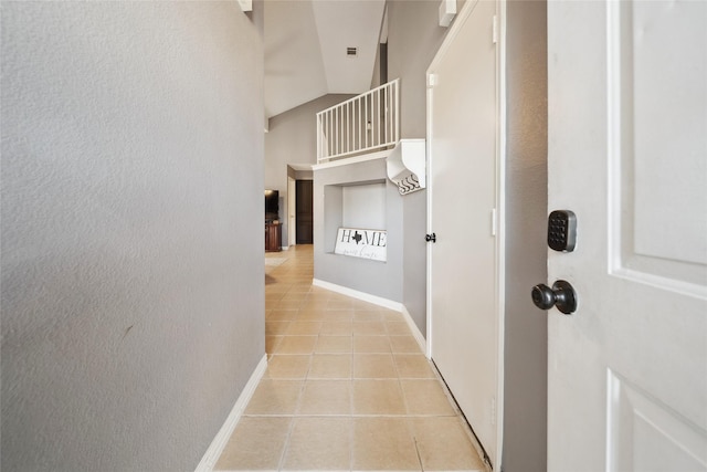 corridor with light tile patterned floors and vaulted ceiling