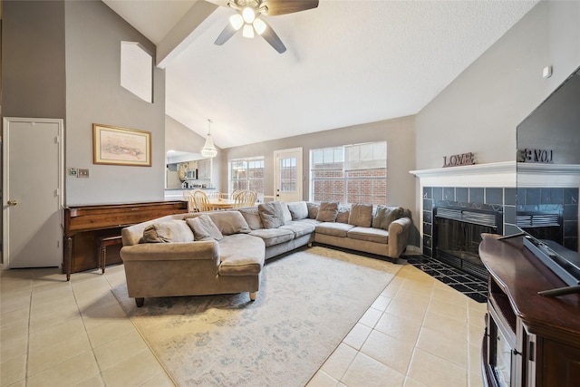 living room with ceiling fan, light tile patterned floors, vaulted ceiling, and a tile fireplace