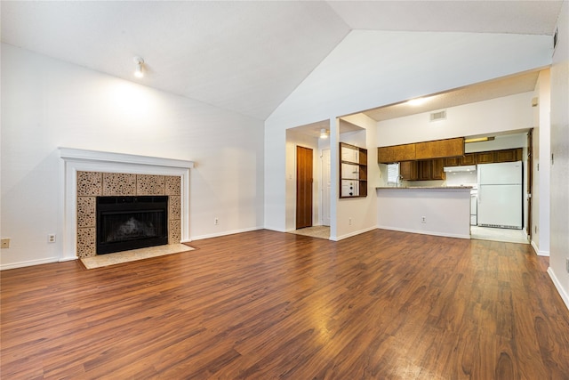 unfurnished living room with dark hardwood / wood-style flooring, a tiled fireplace, and high vaulted ceiling