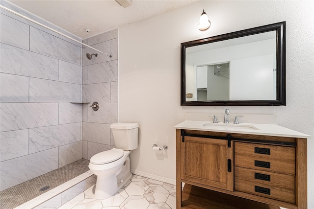 bathroom with toilet, vanity, tiled shower, and a textured ceiling