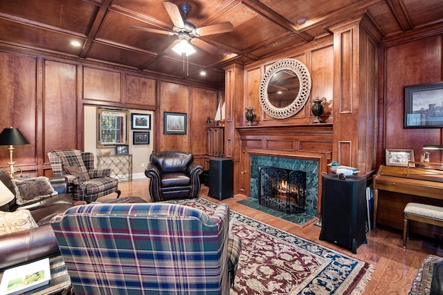 living area featuring wooden ceiling, a ceiling fan, wood finished floors, a fireplace, and coffered ceiling