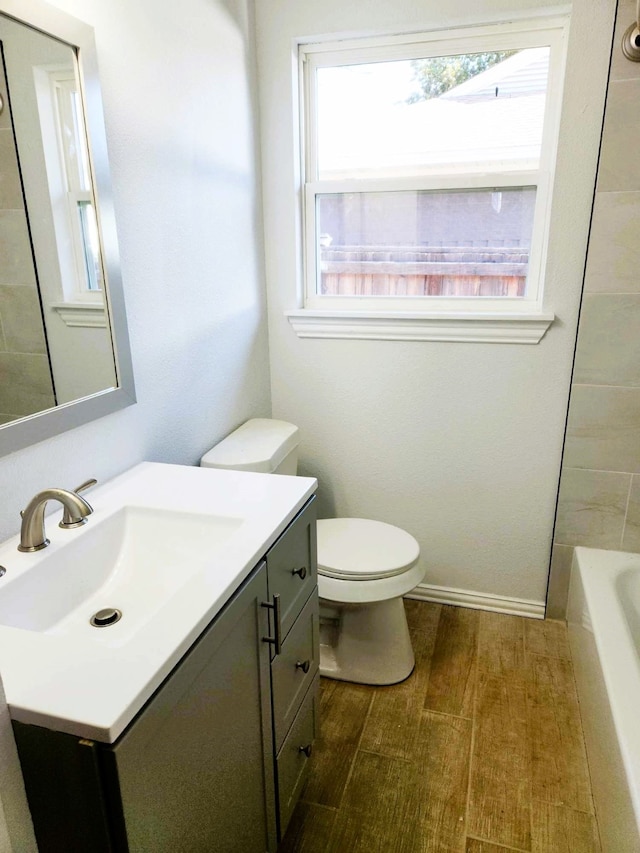 bathroom with vanity, a tub to relax in, hardwood / wood-style flooring, and toilet