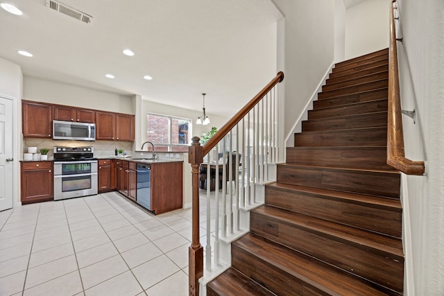 kitchen featuring pendant lighting, appliances with stainless steel finishes, sink, backsplash, and light tile patterned floors