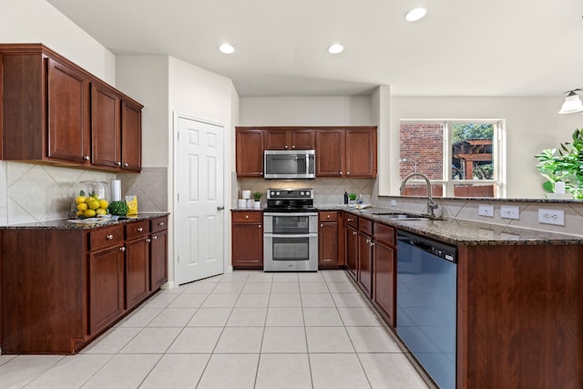 kitchen with sink, decorative backsplash, dark stone counters, and stainless steel appliances