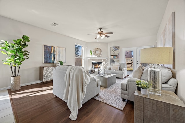 living room featuring ceiling fan, dark wood-type flooring, and a tiled fireplace