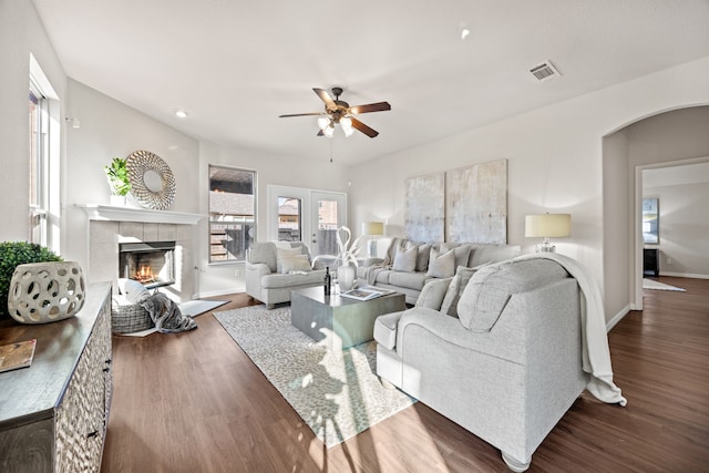 living room featuring a fireplace, dark wood-type flooring, ceiling fan, and french doors