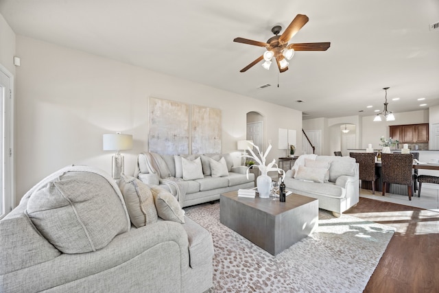 living room with light hardwood / wood-style floors and ceiling fan with notable chandelier