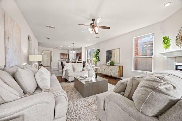 living room featuring ceiling fan, plenty of natural light, hardwood / wood-style floors, and a tiled fireplace