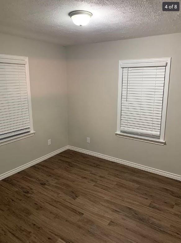 empty room featuring a textured ceiling and dark hardwood / wood-style floors