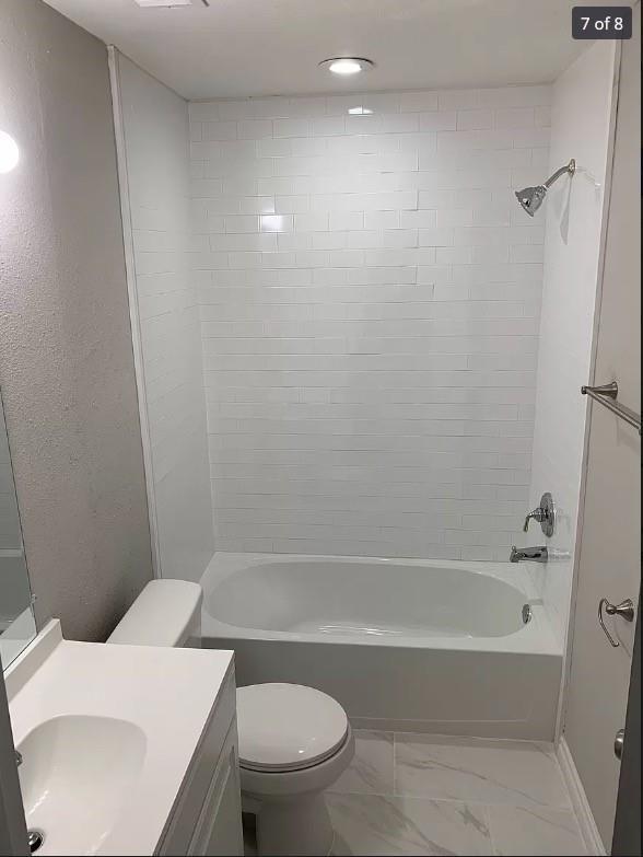 full bathroom with toilet, tiled shower / bath, and vanity