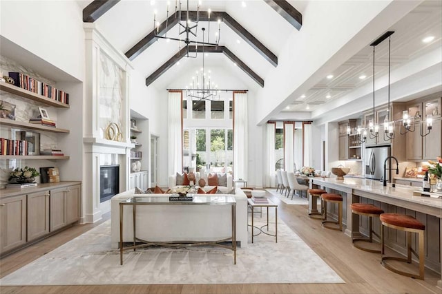 living room featuring high vaulted ceiling, light wood-type flooring, a notable chandelier, and beamed ceiling