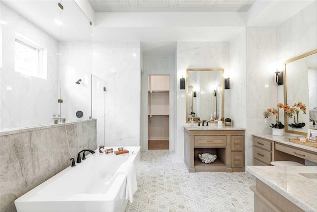 bathroom featuring tile walls, a bath, and vanity