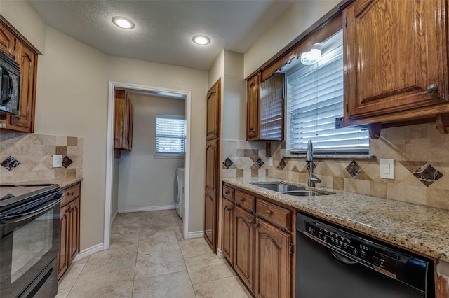 kitchen featuring black appliances, sink, light stone counters, and a textured ceiling