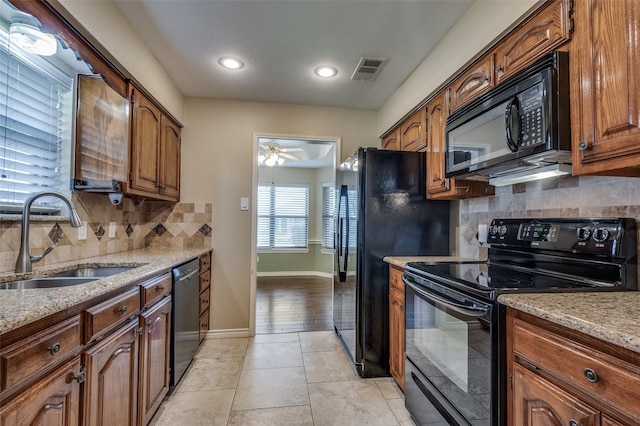 kitchen featuring black appliances, ceiling fan, light stone countertops, and sink