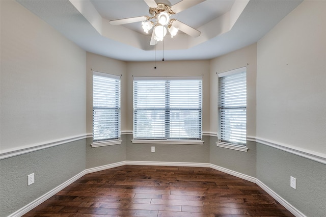 unfurnished room featuring ceiling fan, a tray ceiling, and dark hardwood / wood-style flooring