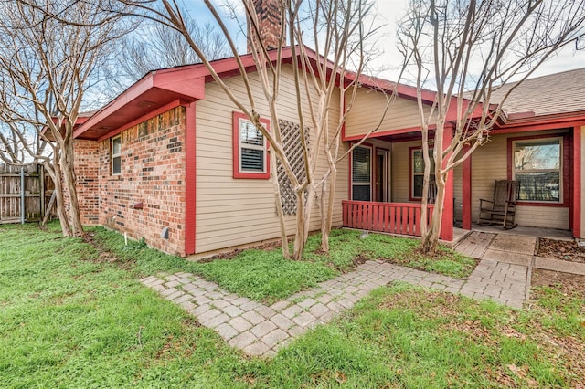 back of property with covered porch and a lawn