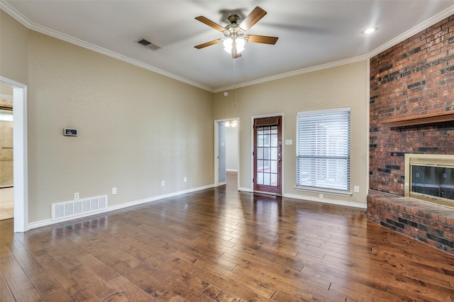 unfurnished living room with dark wood-type flooring, a brick fireplace, ornamental molding, and ceiling fan