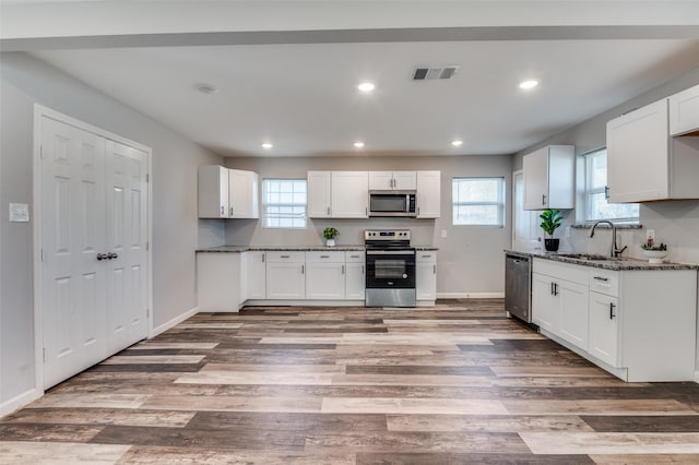 kitchen featuring stainless steel appliances, white cabinets, and dark stone counters