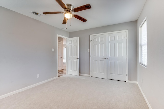 unfurnished bedroom featuring ceiling fan, light colored carpet, multiple windows, and a closet