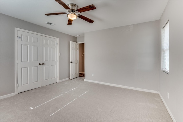 unfurnished bedroom featuring ceiling fan, light colored carpet, and a closet