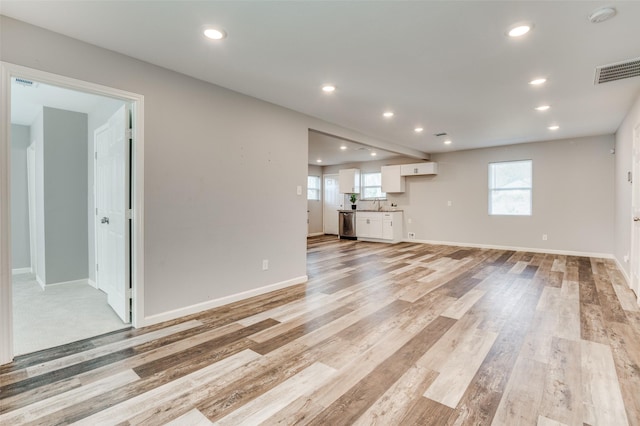 unfurnished living room featuring a healthy amount of sunlight, light hardwood / wood-style floors, and sink