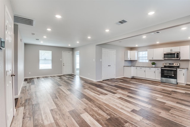 kitchen with stainless steel appliances, light hardwood / wood-style floors, and white cabinets