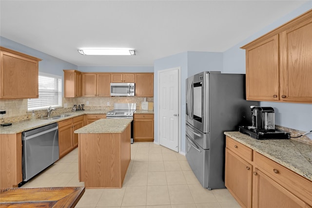 kitchen with sink, stainless steel appliances, a center island, and light stone countertops