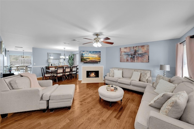 living room with ceiling fan with notable chandelier and hardwood / wood-style floors