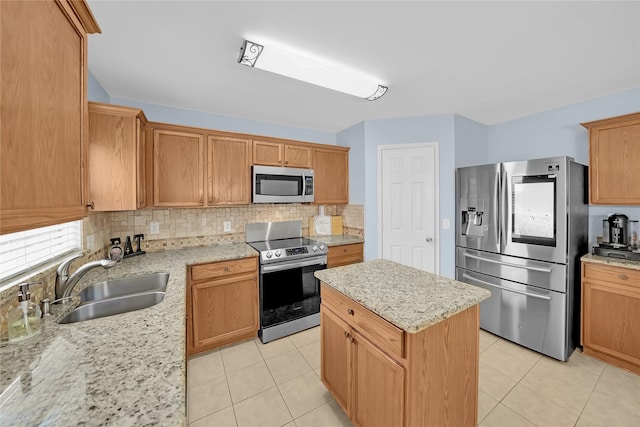 kitchen with light stone counters, sink, stainless steel appliances, and a center island