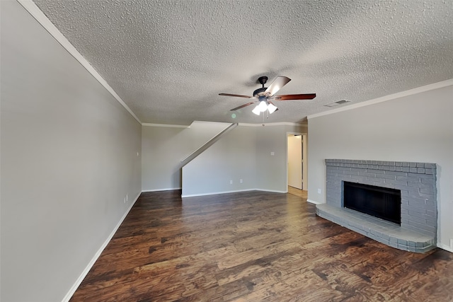 unfurnished living room featuring ceiling fan, a fireplace, crown molding, dark wood-type flooring, and a textured ceiling