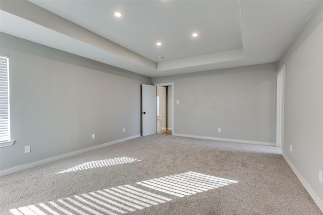 carpeted empty room with a raised ceiling