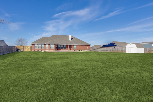 rear view of property featuring a patio area, a storage unit, and a yard