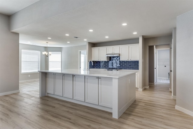 kitchen with decorative backsplash, a spacious island, white cabinetry, and an inviting chandelier