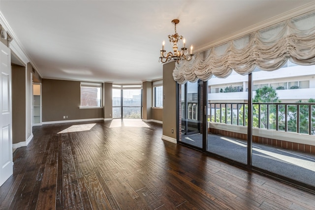 empty room with dark hardwood / wood-style flooring, ornamental molding, and a notable chandelier